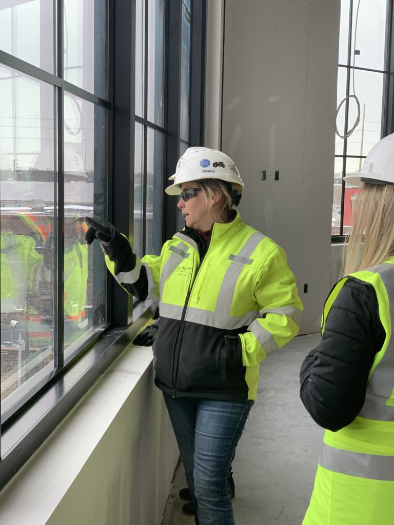 Women construction worker pointing at something through the window